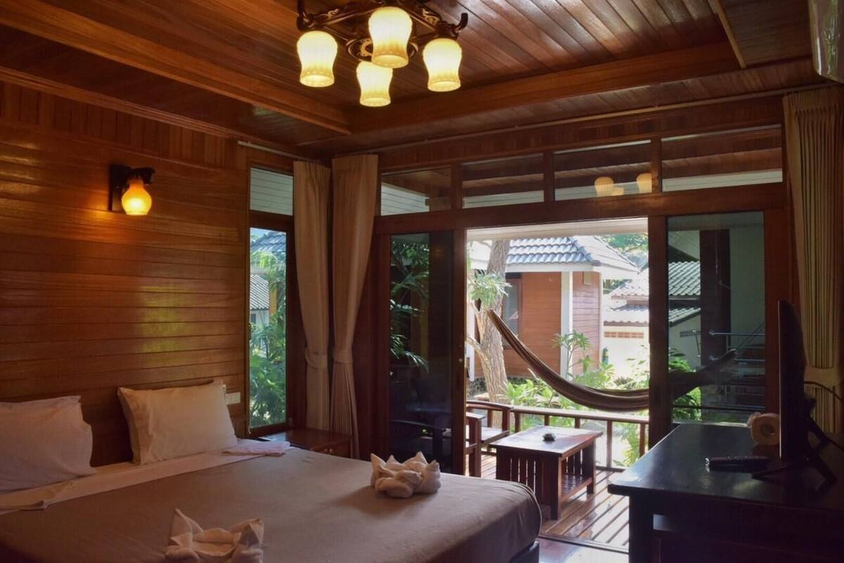 Una habitación de madera con una cama, un escritorio y ventanas amplias.