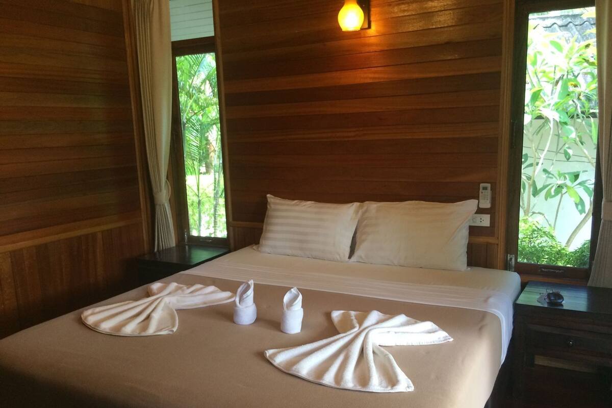 Una cama bien hecha con sábanas y toallas blancas dispuestas en un diseño decorativo.