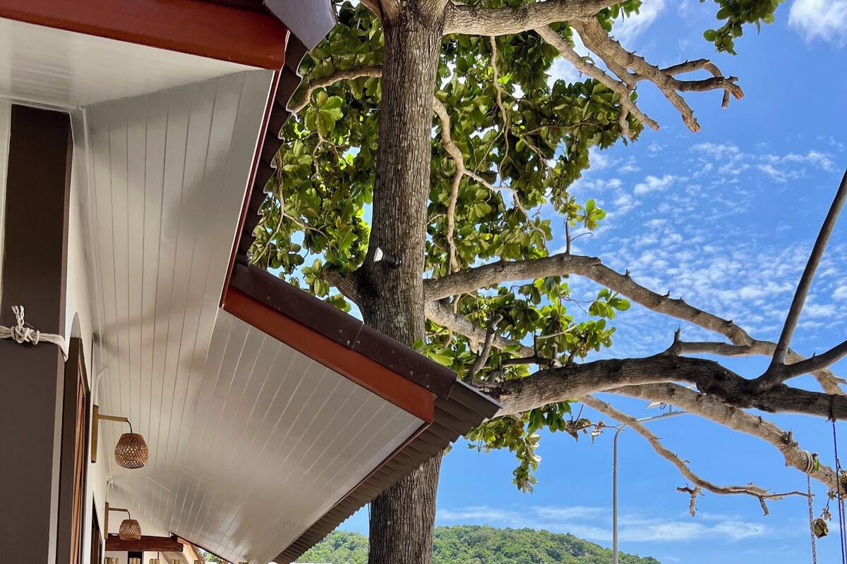 Una terraza de madera con una escalera de piedra que conduce a un espacio cubierto con asientos, con vista a una playa y al océano.