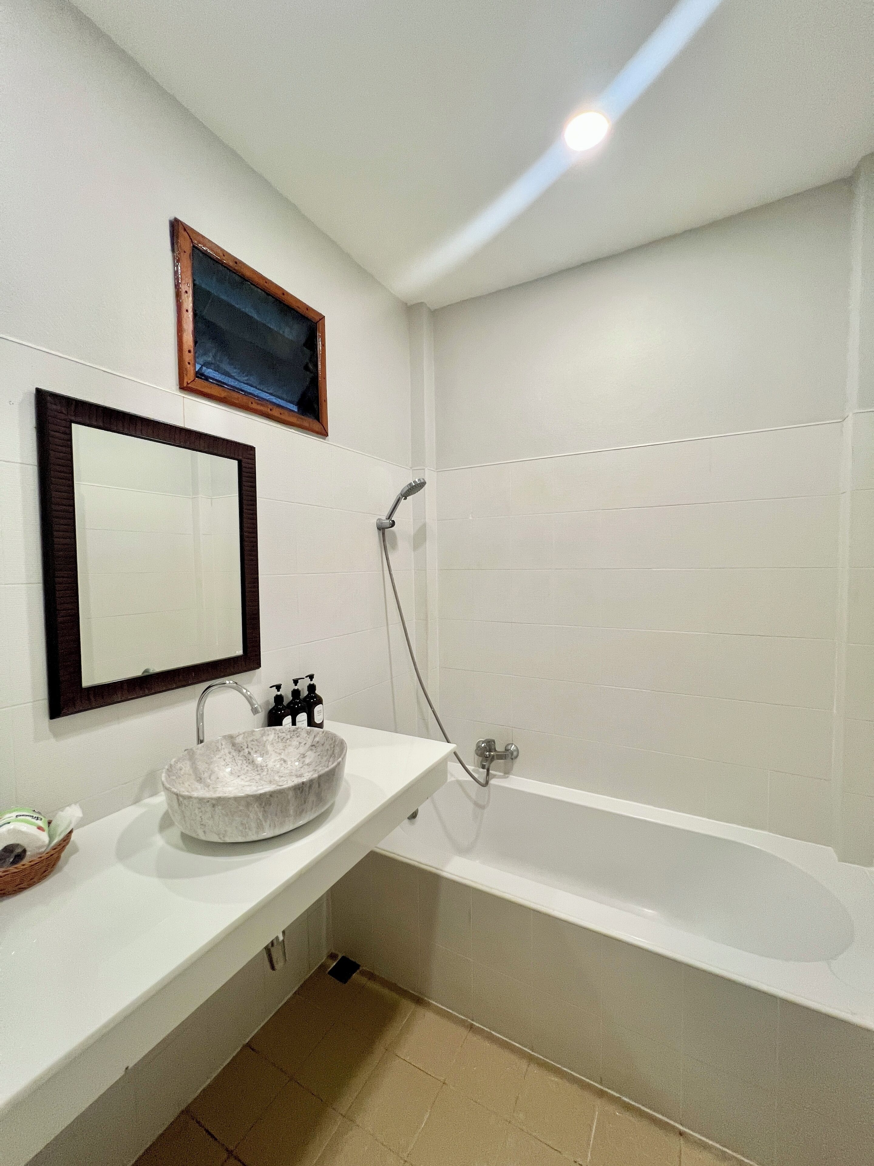 Ein modernes Badezimmer mit einem weißen Waschbecken, einem großen Spiegel und einer Badewanne.