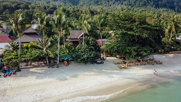 Ein Strand mit Palmen, Strandhütten und Häusern.