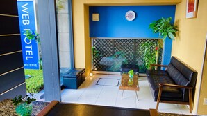 Un hall d’hôtel moderne avec un mur bleu, un comptoir d’accueil, un canapé et une plante en pot.
