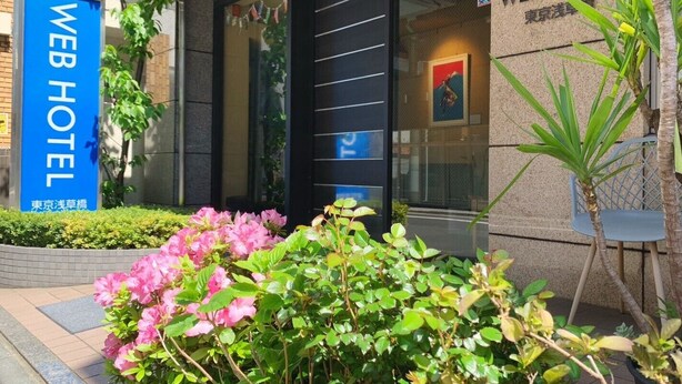 L’entrée d’un hôtel, avec une enseigne indiquant « WEB HOTEL » et un panneau précisant « 5e étage, gare de Tokyo ».