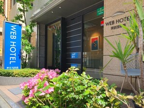 A hotel entrance with a sign reading 'WEB HOTEL' and a sign indicating 'Tokyo Station 5th Floor.'