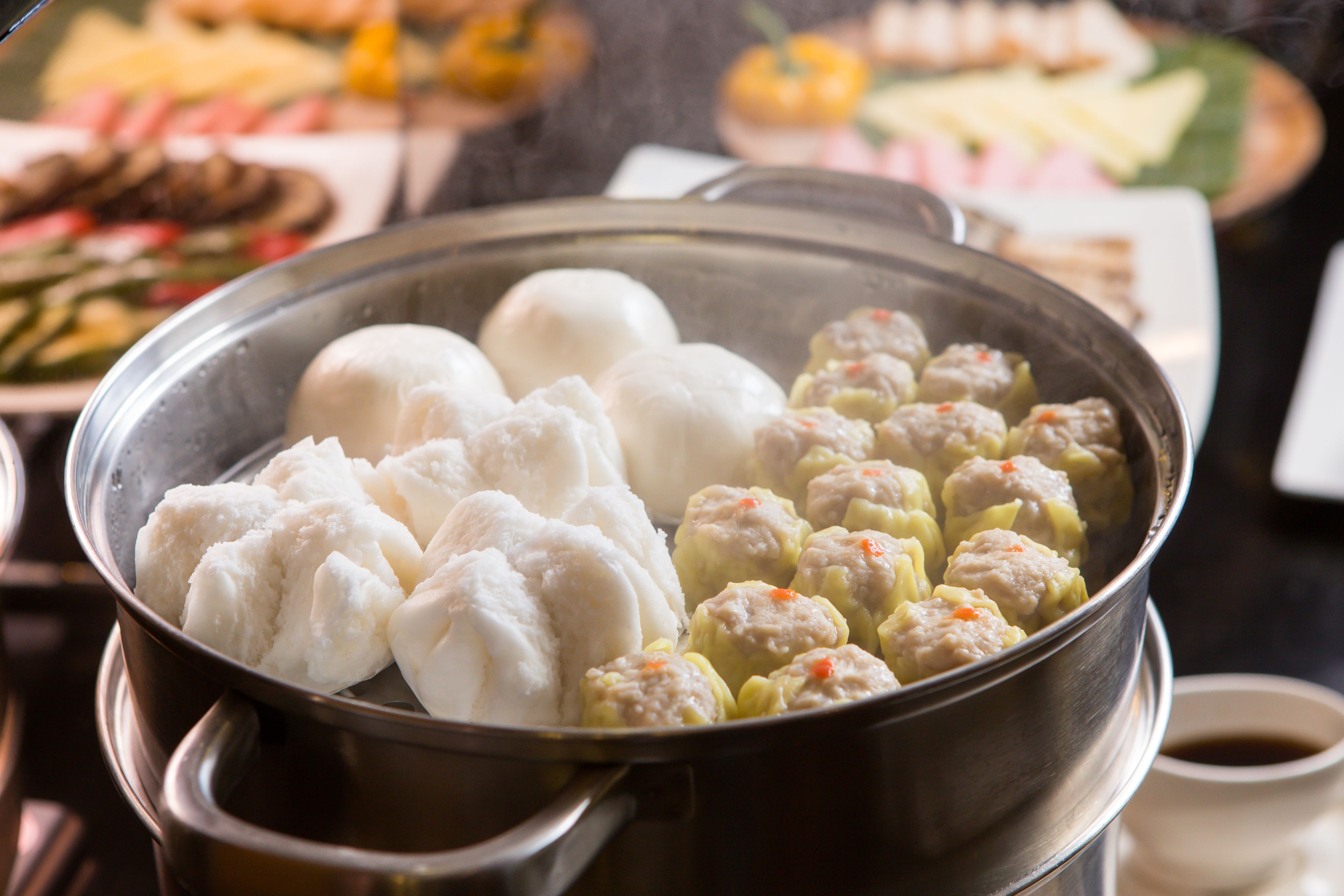 A pot of food with dumplings and steamed buns.