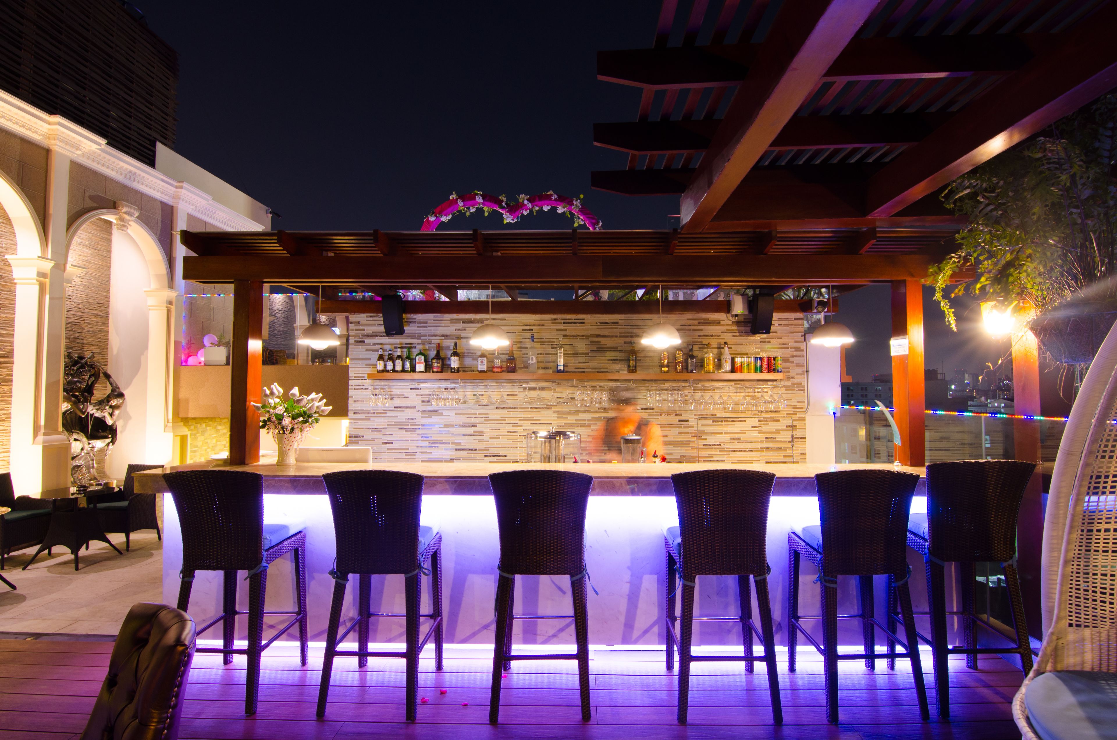 An outdoor bar area with a stone countertop, bar stools, and a view of the city at night.