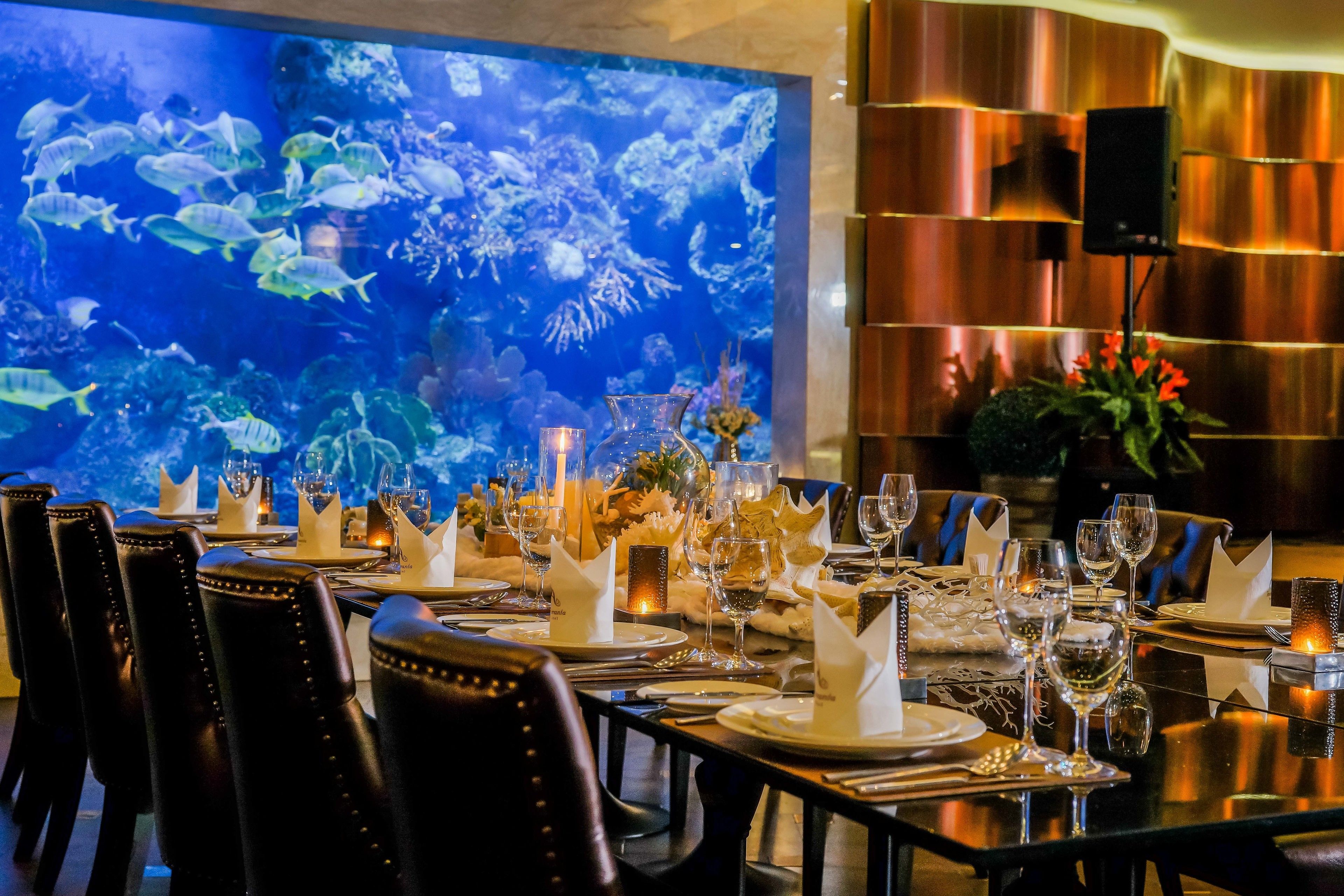 A dining area with a large aquarium wall, neatly set tables, and modern decor.