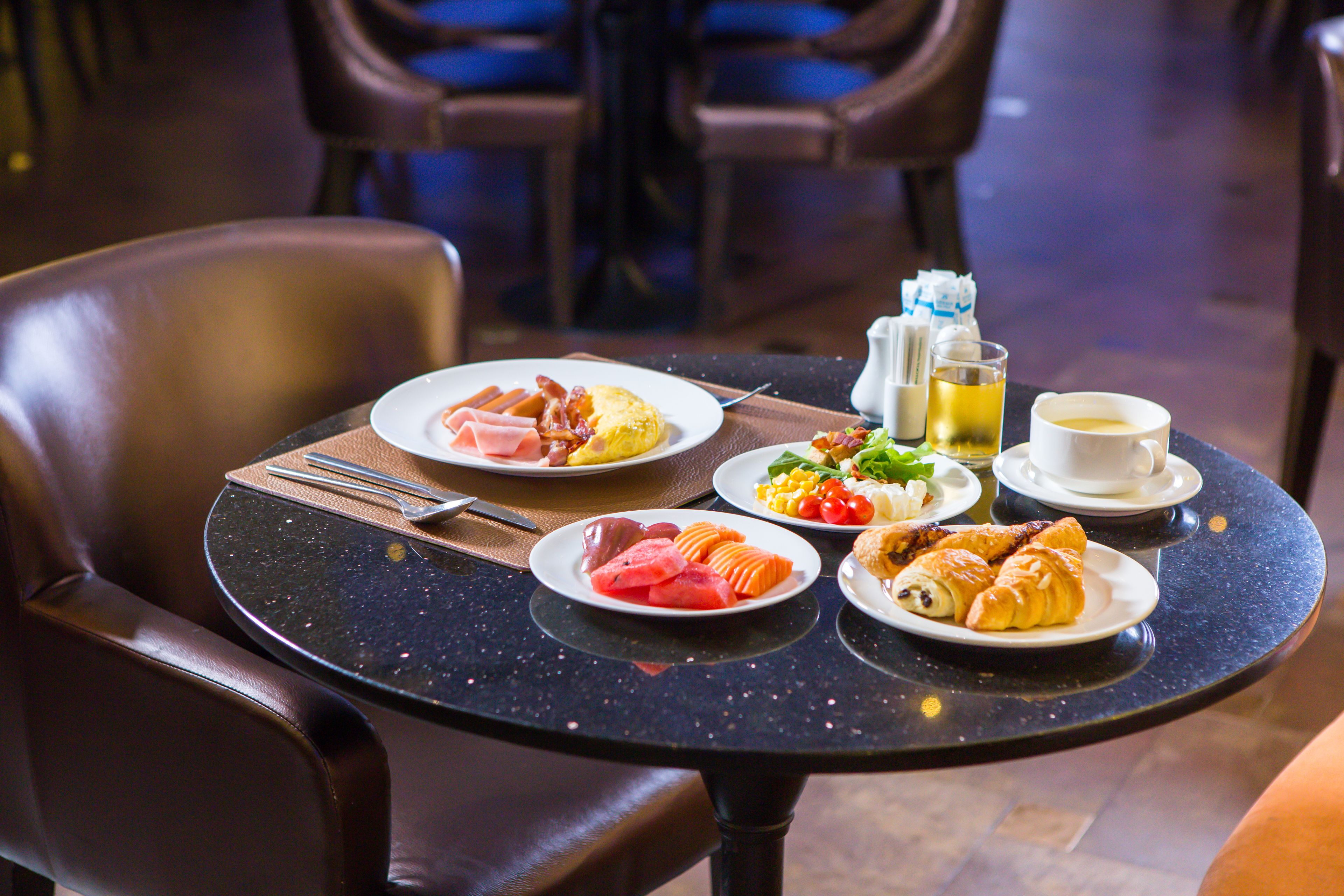 A dining table with plates of food, a cup of coffee, and a bottle of water.