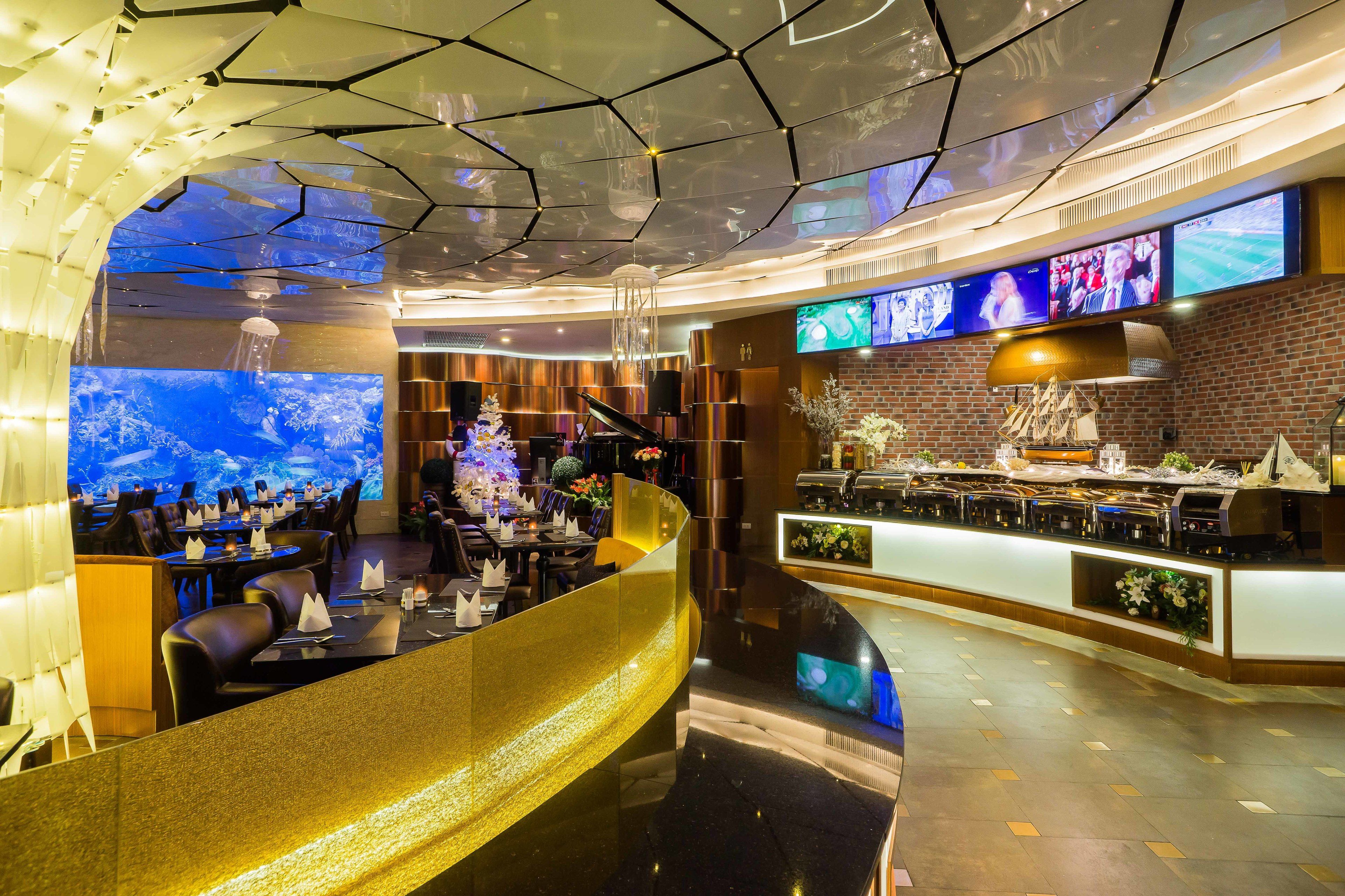 Un restaurante moderno con techo alto, múltiples pantallas y una zona de bar.