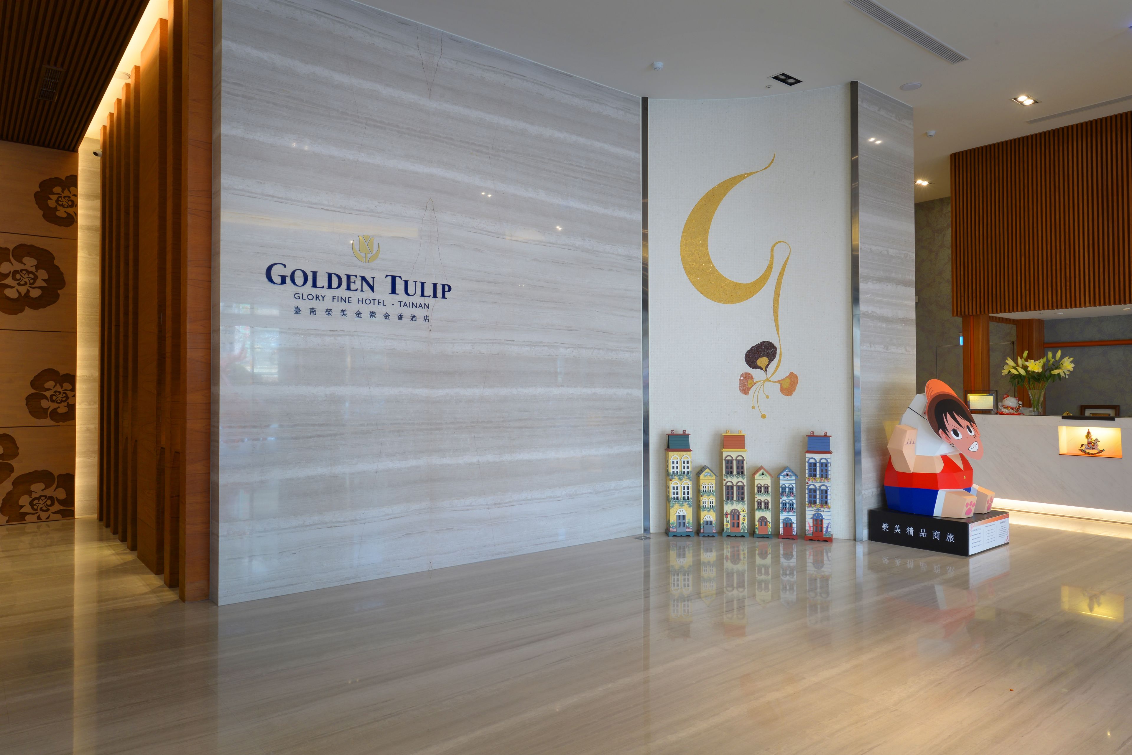 A hotel reception area with a modern design, featuring a large sign for the Golden Tulip hotel, a crescent moon decoration, and a small figurine of a character.