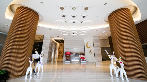 A hotel lobby with high ceilings, wooden columns, and a modern chandelier. - Golden Tulip Glory Fine Hotel (Tainan)