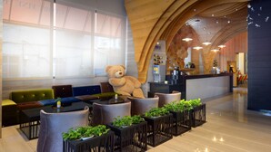 Een moderne lobby met een grote knuffelbeer, zitgedeeltes en een receptiebalie.