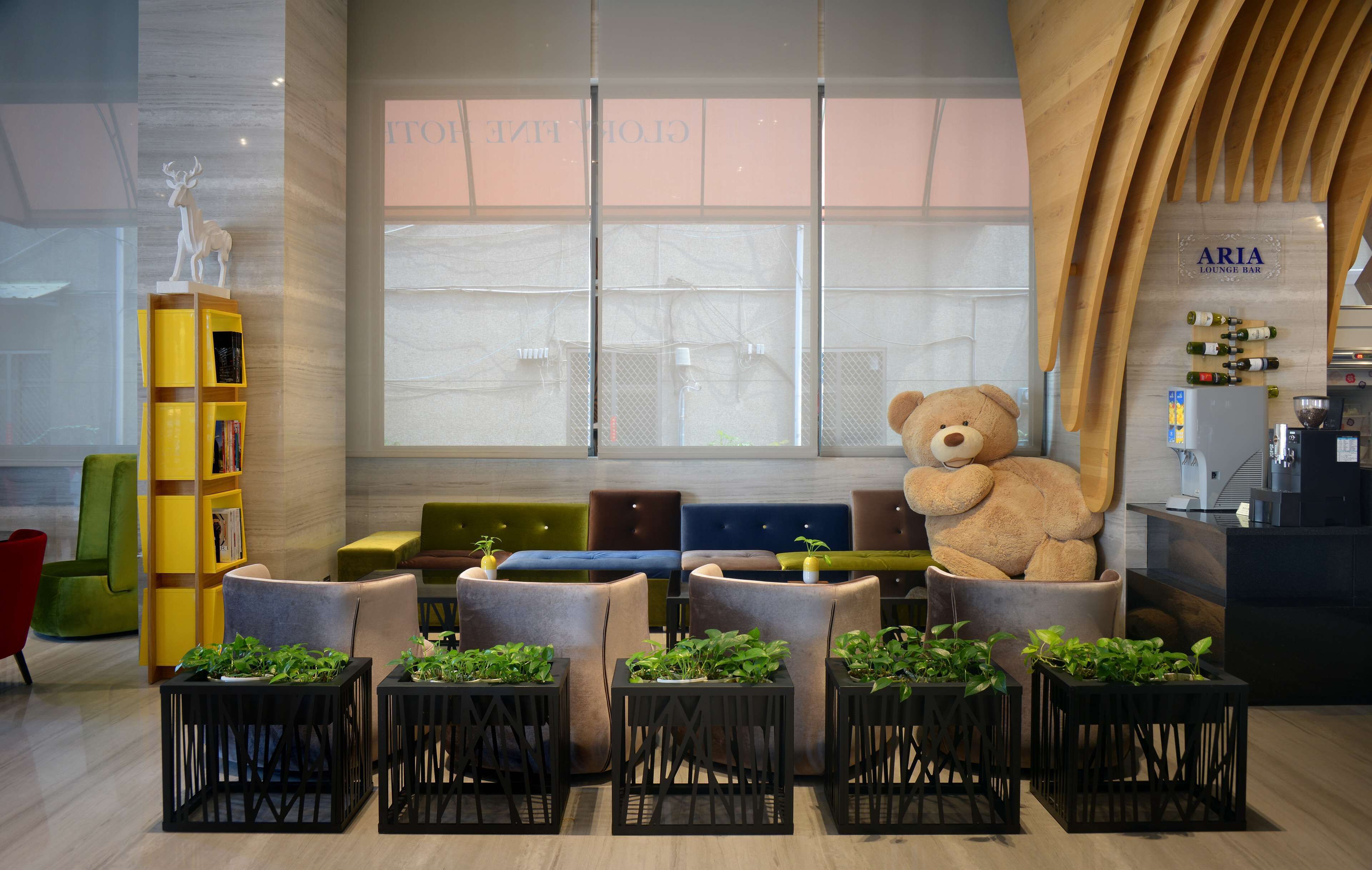 Un espace détente moderne avec des fauteuils confortables, un grand ours en peluche et une bibliothèque.