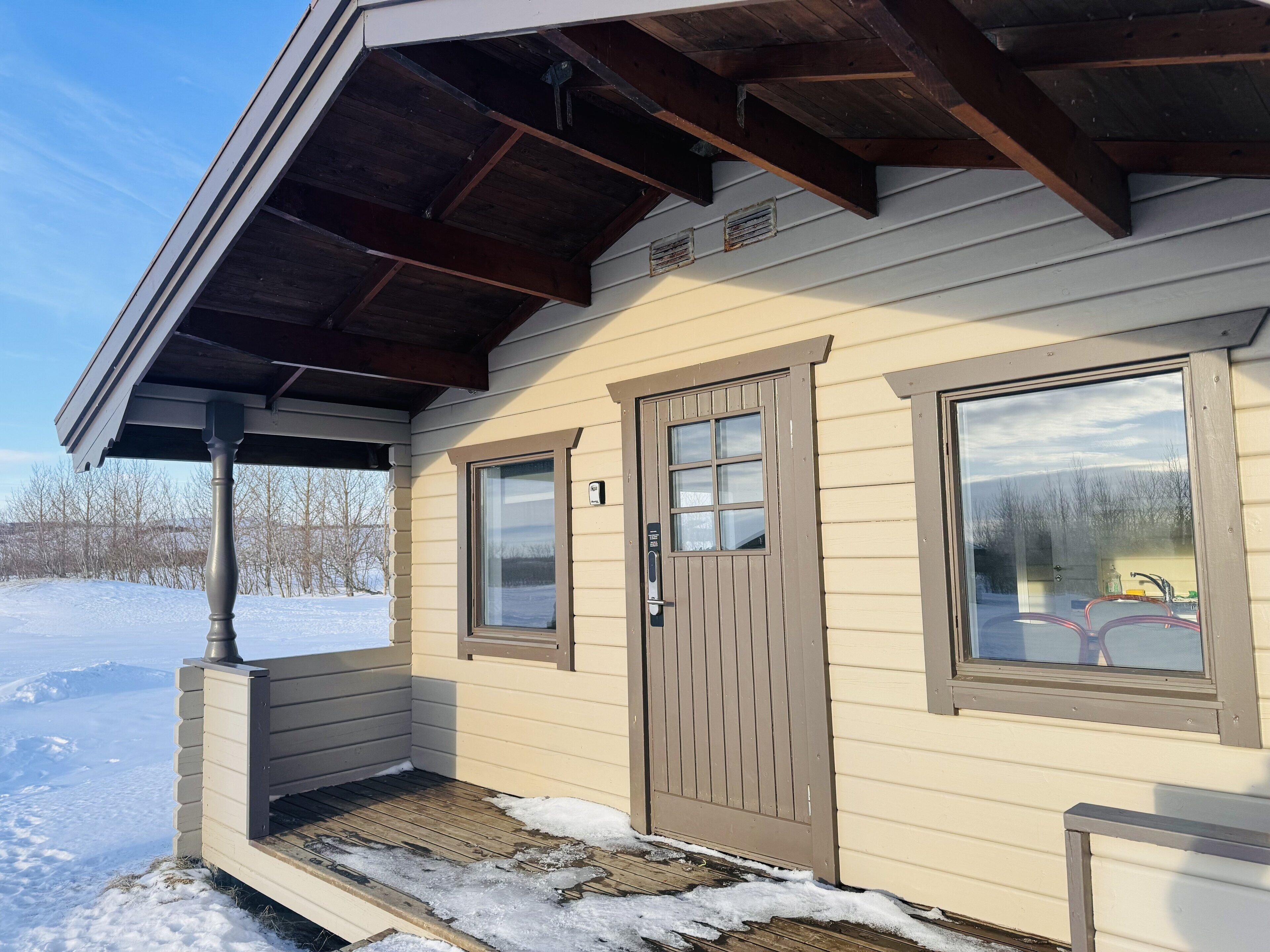 A small cabin with a wooden porch, a sliding door, and two windows.