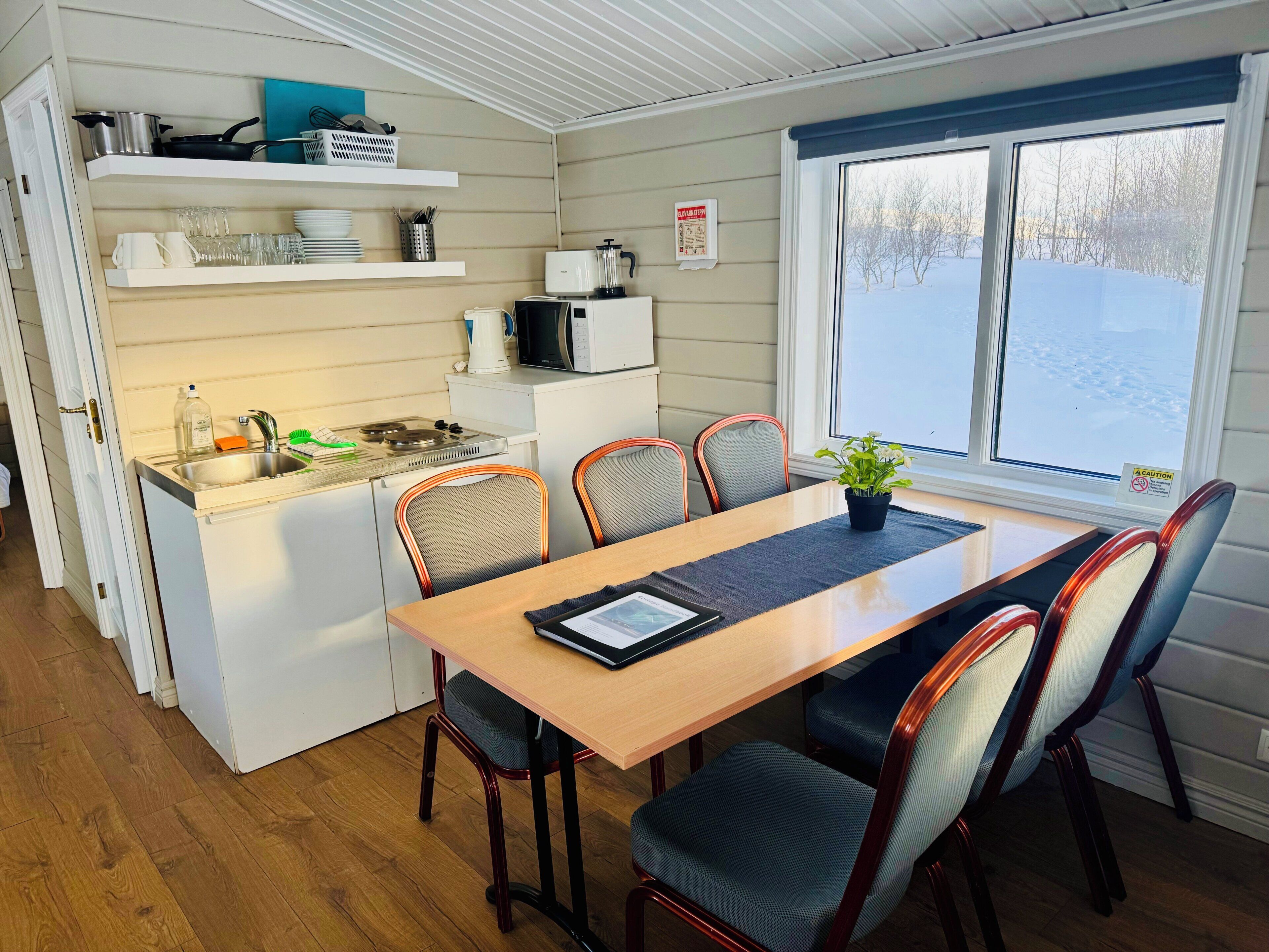 A compact kitchen with a dining area, a microwave, and a window with a view of a snowy landscape.