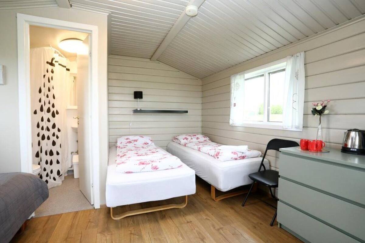 A compact room with two single beds, a small desk, a chair, and a window with curtains.