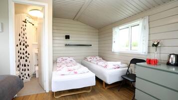 Un alojamiento pequeño, con una habitación individual equipada con dos camas individuales, un escritorio, una silla y una ventana.