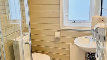 Een badkamer met een toilet, wastafel en een raam.
