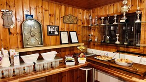 A wooden interior with a bar area, framed certificates, and trophies on shelves. - Hellisholar Cottages (Rangárþing eystra)