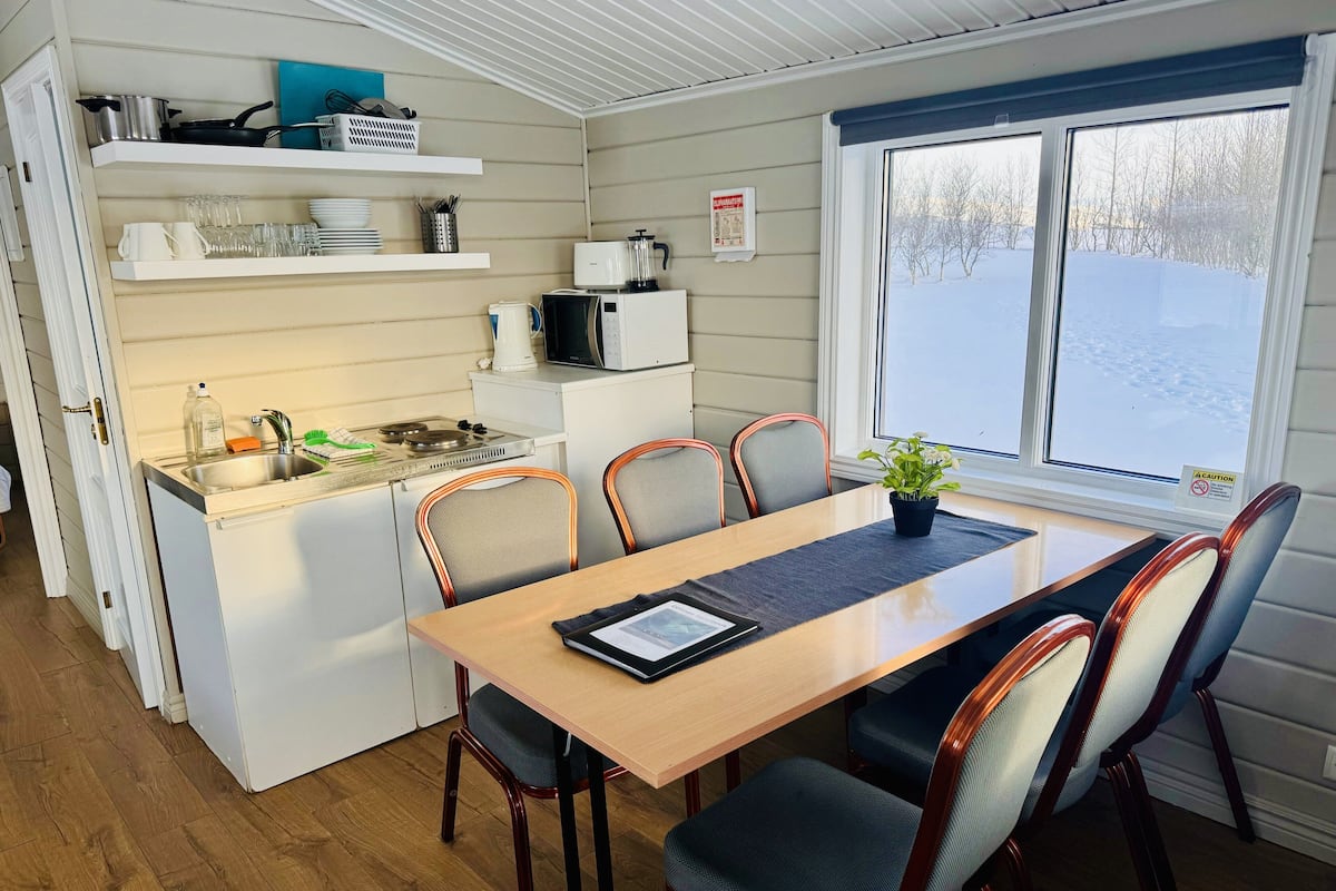 A compact kitchen with a dining area, including a stove, sink, and microwave.