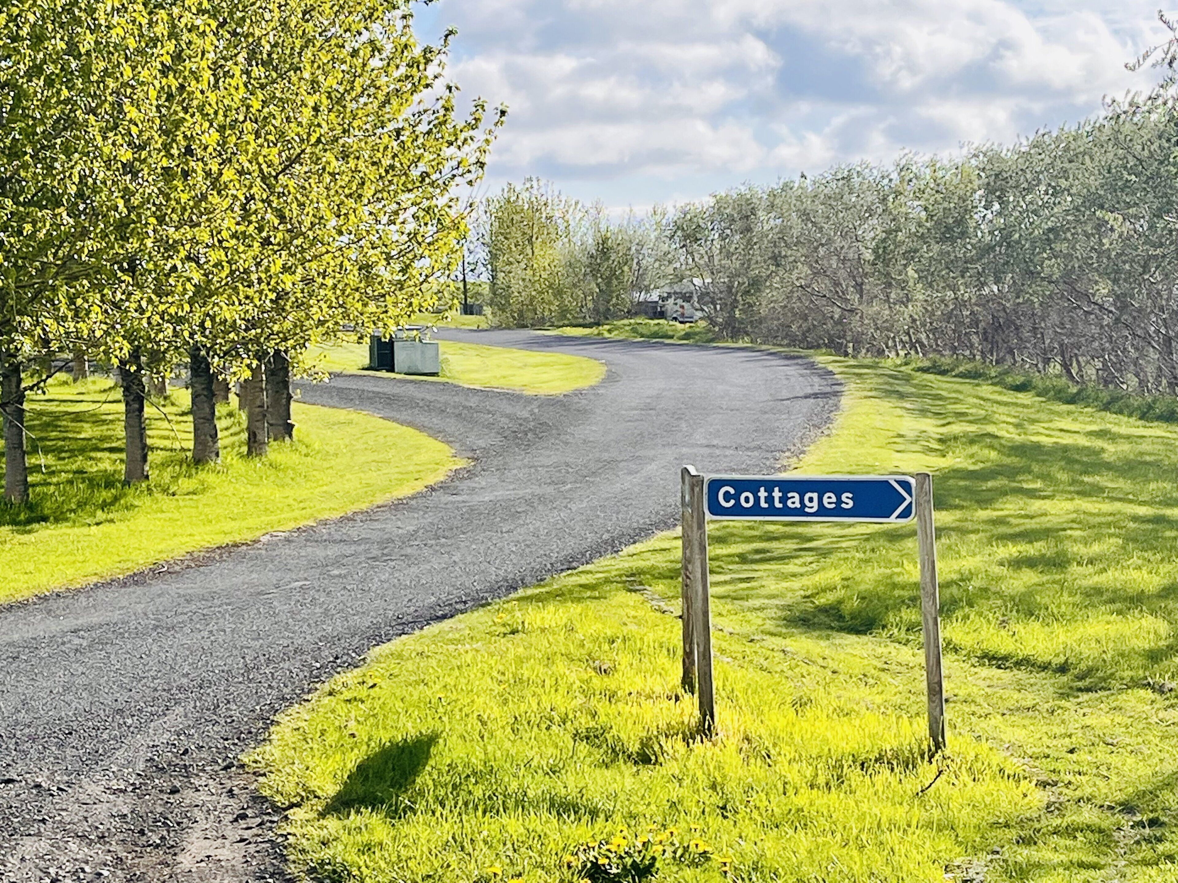 A road leading to cottages with a sign indicating the direction.