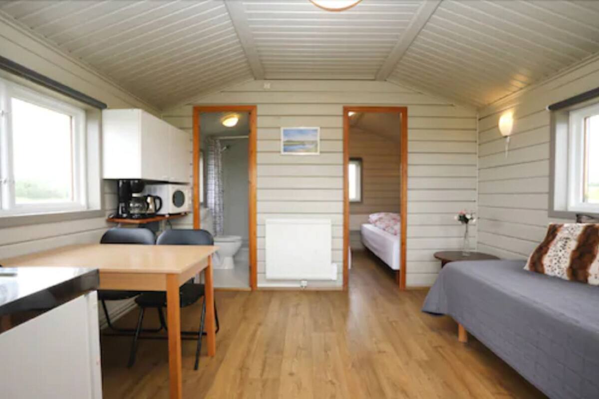 A compact room with a kitchenette, a bed, a small table, and a chair.