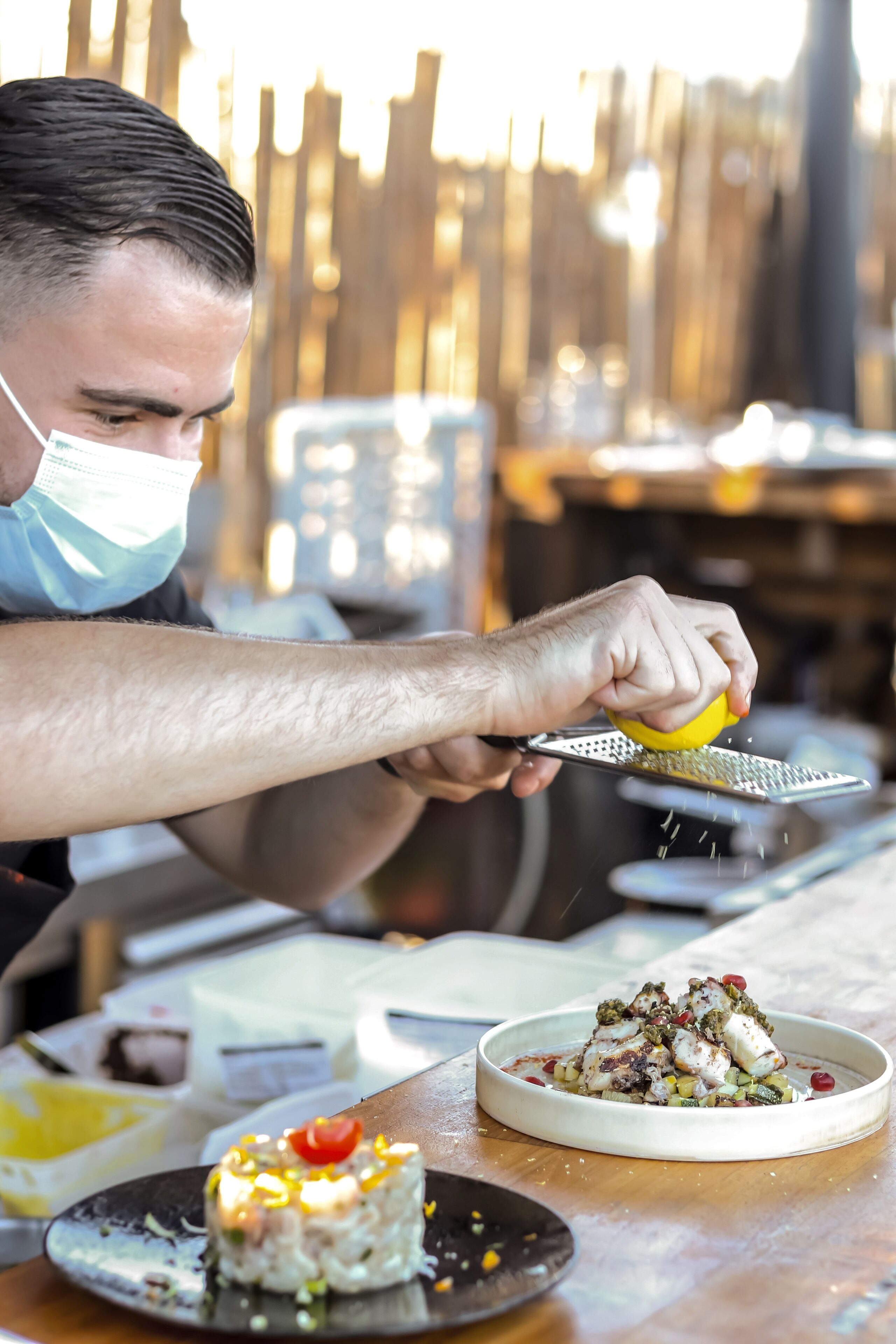 A person grating cheese over a dish.