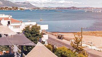 A coastal view with a road leading to a beach, a mountain in the background, and a clear sky.
