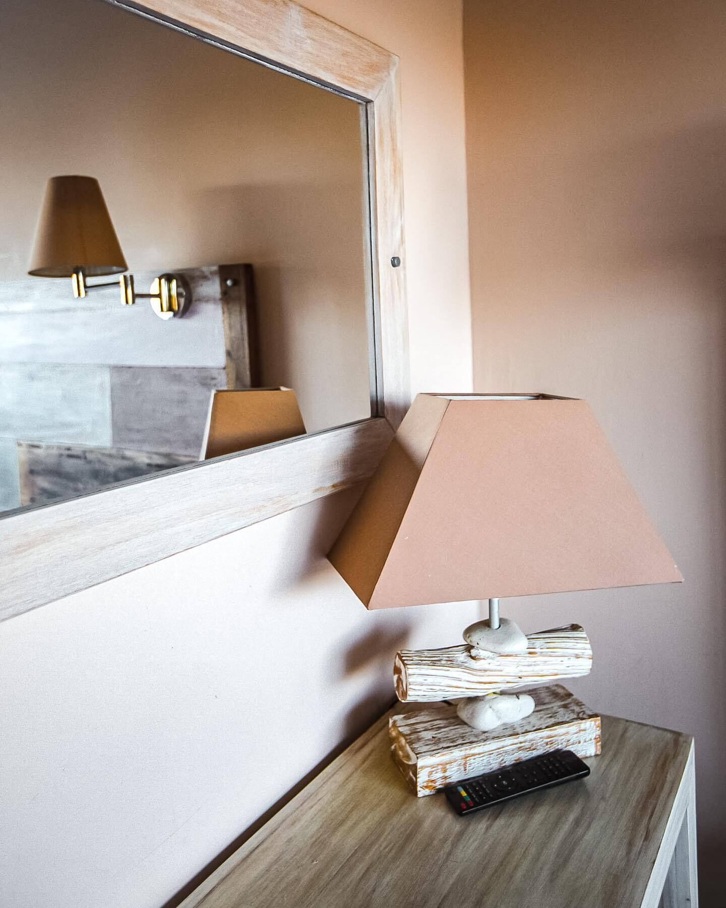 Een nachtkastje met een lamp, een afstandsbediening en een stapel boeken.