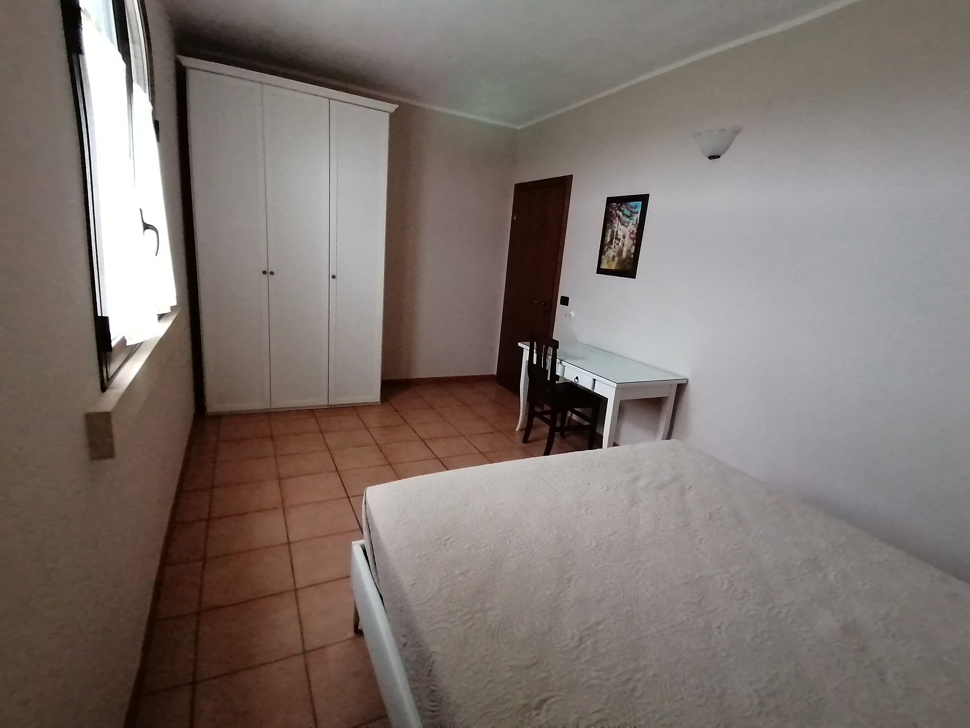 A room with a bed, a desk, and a wardrobe.