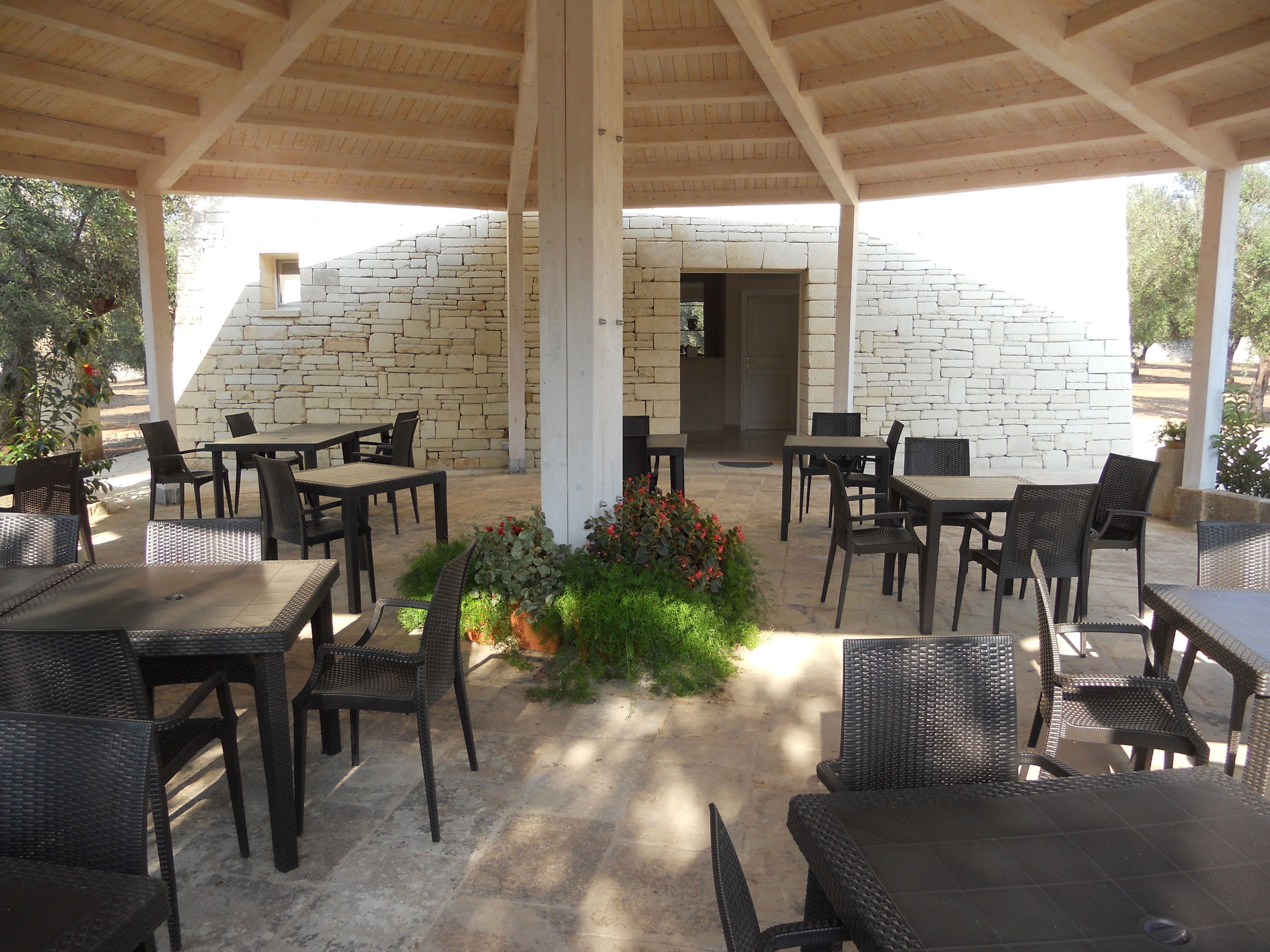 An outdoor patio area with stone walls, wicker furniture, and a central flower arrangement.