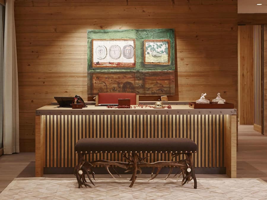 Un mostrador de recepción con detalles de madera, un banco y una obra de arte en la pared.