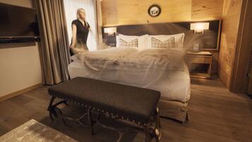 Una habitación de hotel con una cama grande, un banco, un televisor y paneles de madera.
