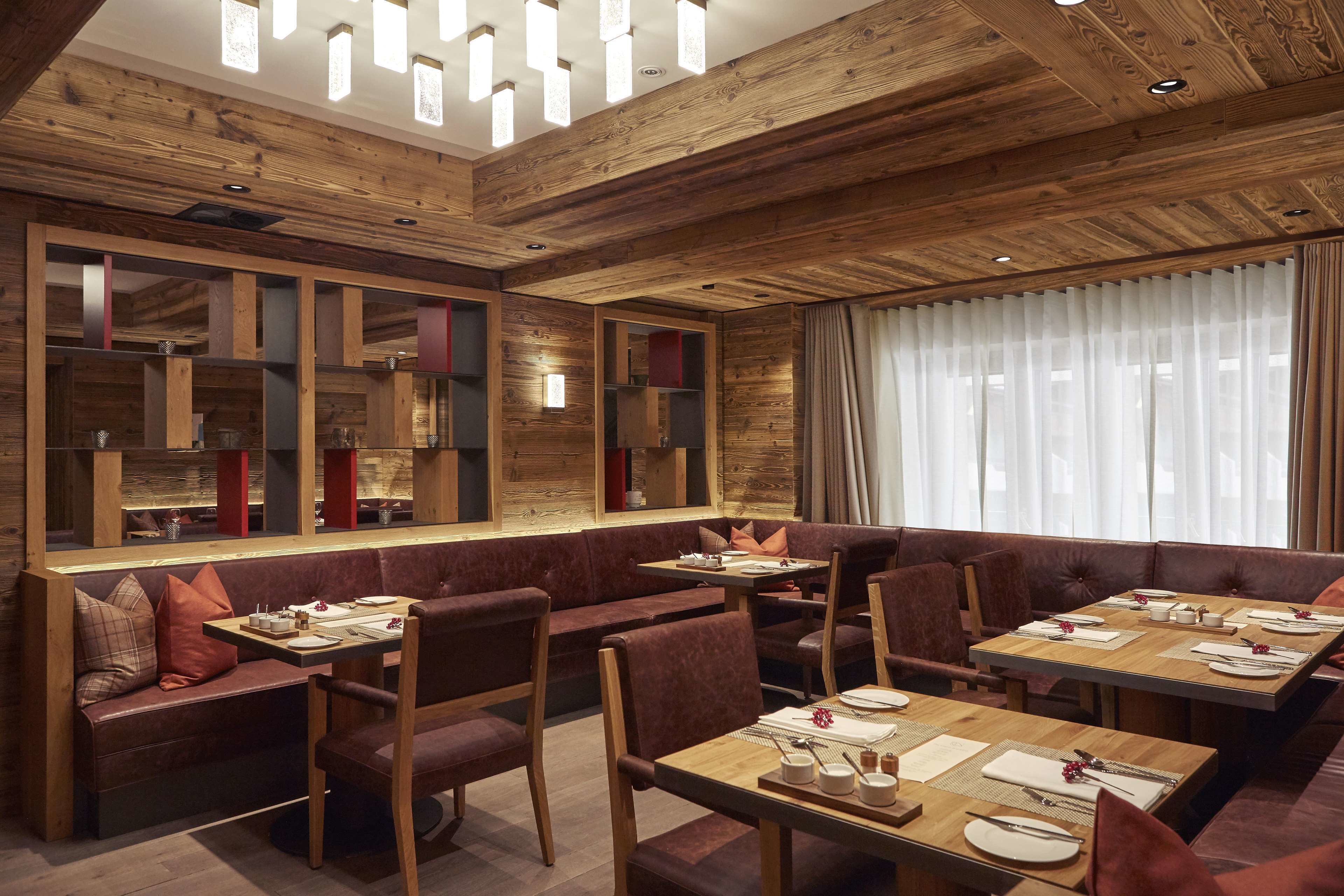 Un restaurant avec des boiseries, des sièges rembourrés et une grande fenêtre agrémentée de rideaux.