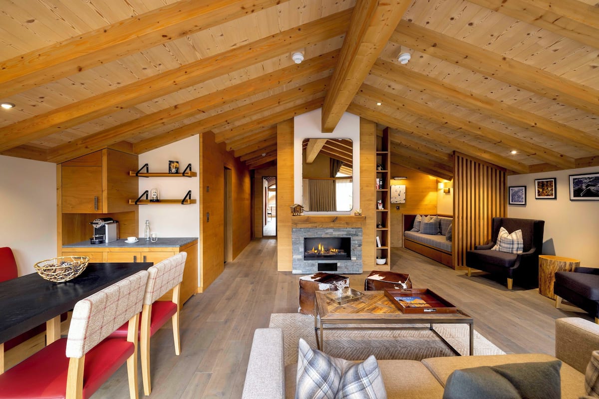 Un vaste espace de vie agrémenté d’une cheminée, de poutres apparentes en bois et d’un coin salon confortable.
