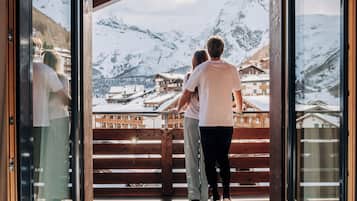 Ein Paar steht auf einem Holzbalkon mit Blick auf die Berge.