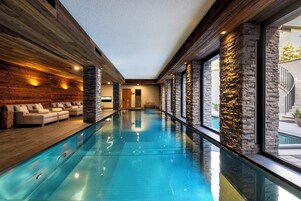 Una piscina cubierta, una piscina al aire libre, tumbonas