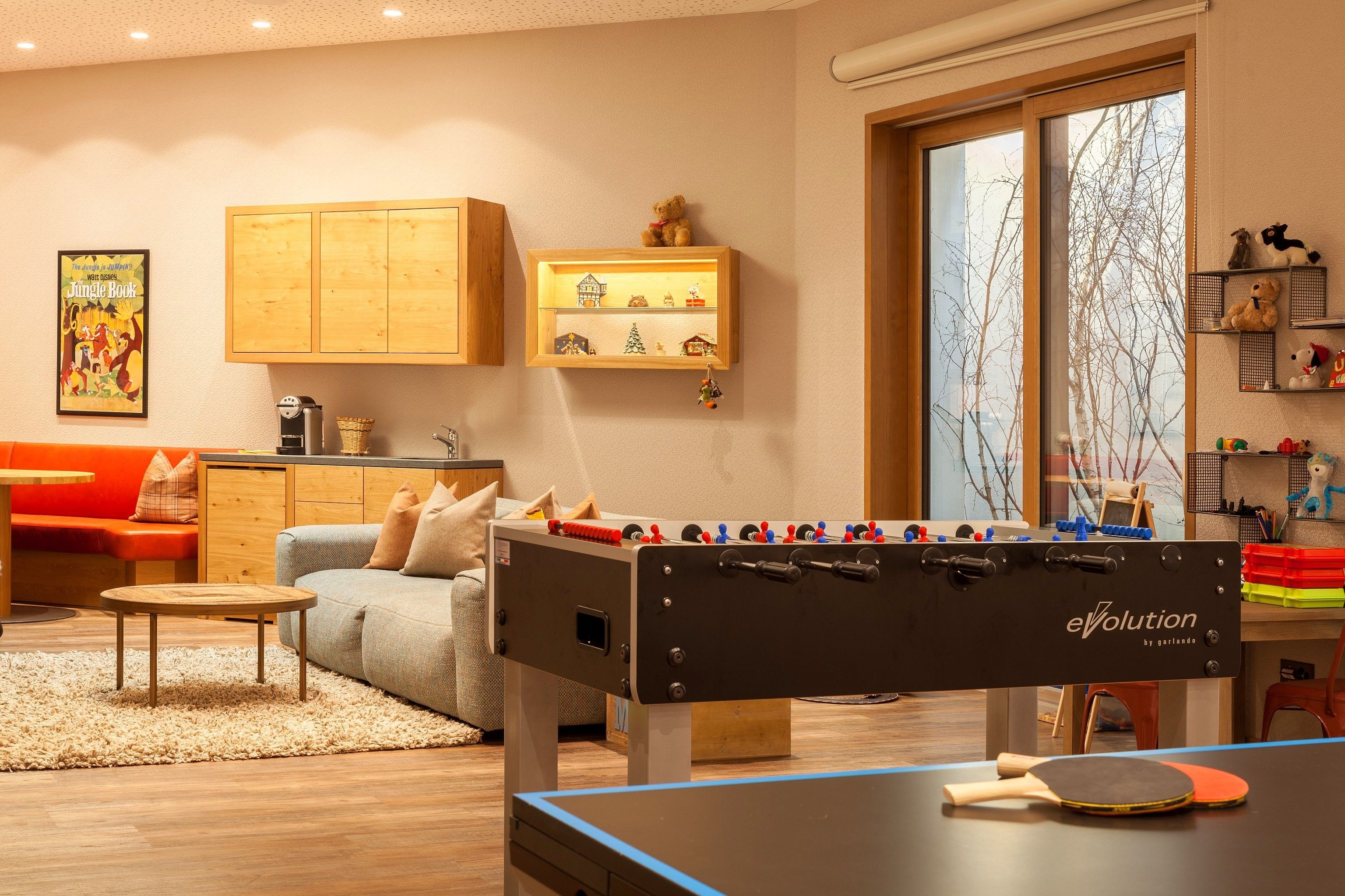 Ein gemütliches Wohnzimmer mit einem Tischfußballtisch, einem Pongtisch und einem Sofa.