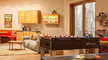 Ein gemütliches Wohnzimmer mit einem Tischfußballtisch, einem Pongtisch und einem Sofa.