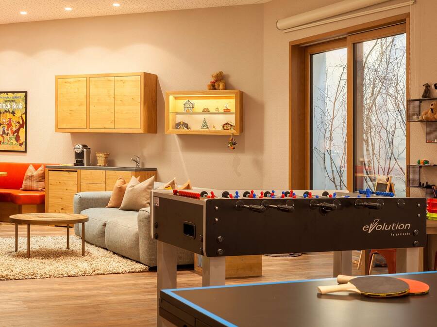 A cozy living room with a foosball table, a ping pong table, and a sofa.