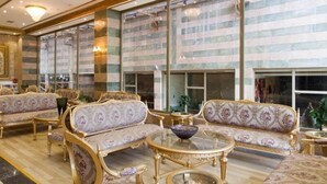 A luxurious interior with ornate sofas, a glass coffee table, and a large window offering a view.