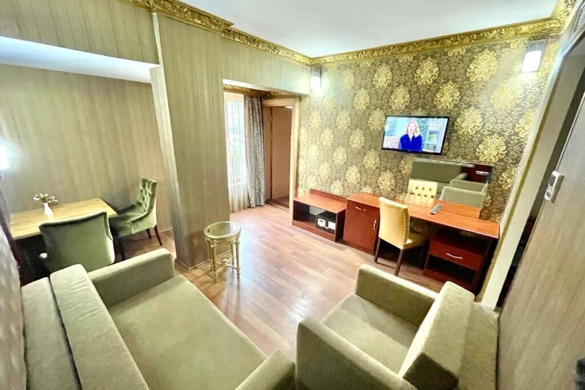A hotel room with a TV, a desk, and two sofas.