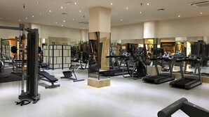 A gym with various exercise equipment, including treadmills and weight machines, and a mirrored wall.