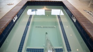 Una piscina rectangular con azulejos azules y un desagüe central.
