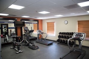 A gym with treadmills, elliptical machines, and dumbbells.