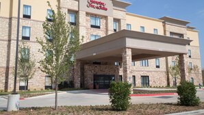 Edificio de Hampton Inn & Suites con fachada de piedra, múltiples ventanas y entrada cubierta.