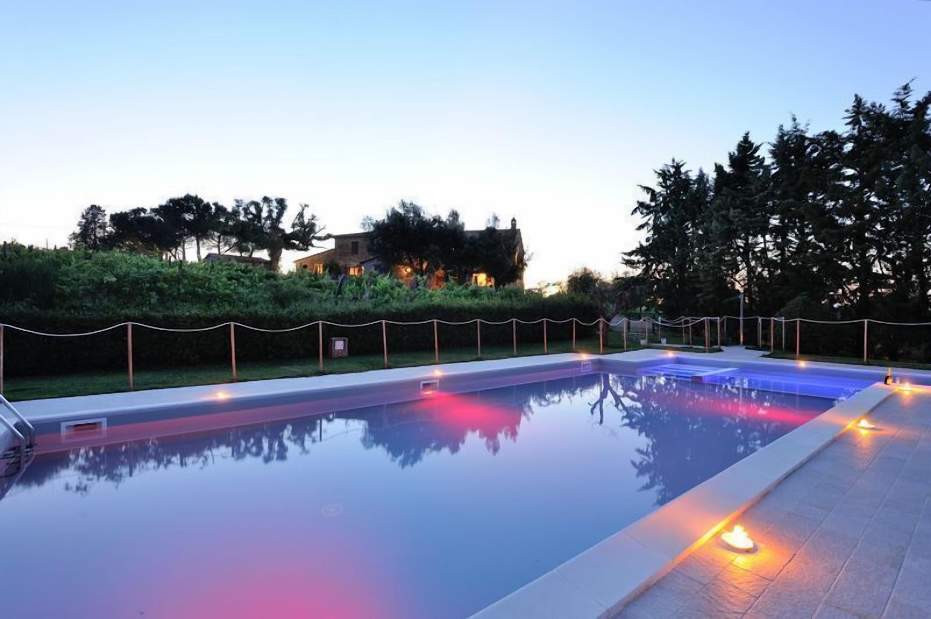 A rectangular swimming pool with a tiled edge, surrounded by a low hedge and a rope barrier.
