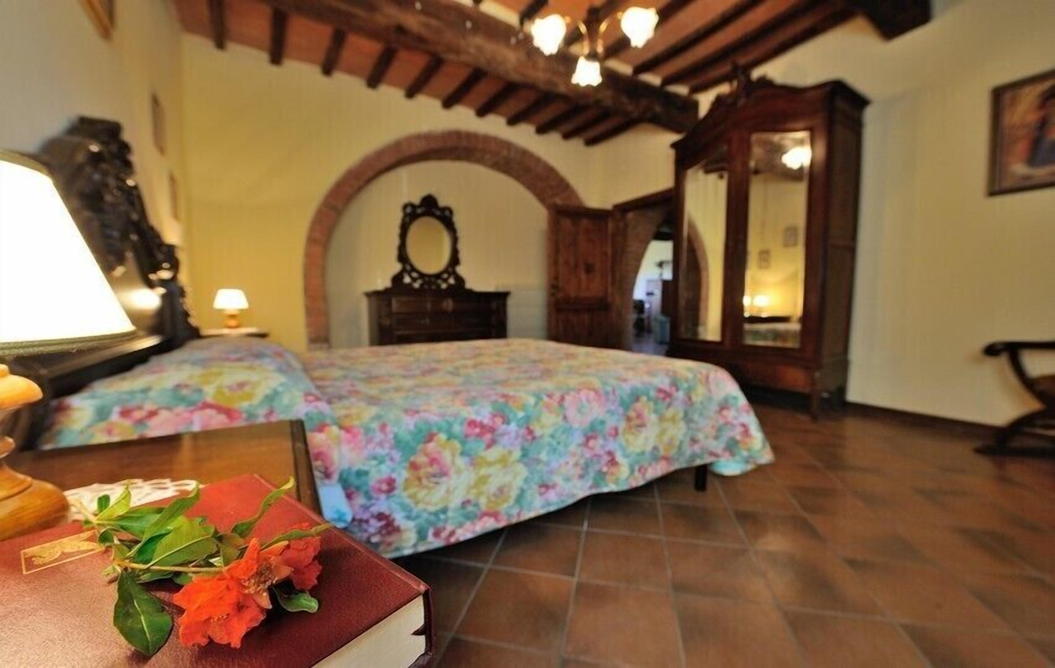 A room with a bed, a wooden arched doorway, a mirror, and a lamp.
