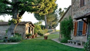 A stone building with a rustic exterior, a small garden area with a bench, and potted plants. - Agriturismo Antico Podere Siliano (Citta della Pieve)