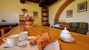 A cozy dining area with a wooden table, two white cups, a croissant, and a tureen of soup. - Agriturismo Antico Podere Siliano (Citta della Pieve)